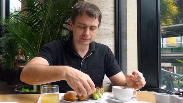 Homem feliz desfrutar brekfast, comer donut doce, pão, mastigar, sentar-se no restaurante, café — Vídeo de Stock