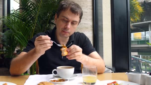 Jovem adulto comendo pão fresco assado com geléia de baga no café da manhã no restaurante — Vídeo de Stock