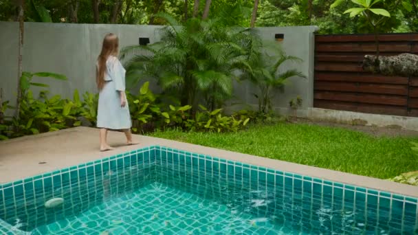 Vrouw wandelen langs rand van het zwembad tussen groen. Welzijn, Harmonie — Stockvideo