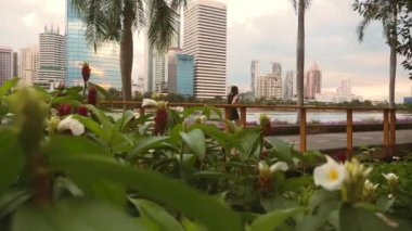 Arka planda gökdelenlerle birlikte şehir parkında koşan Asyalı kadınların arka planı