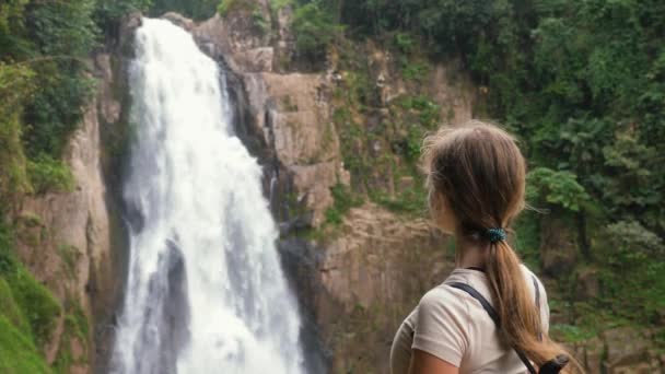 Joven mujer feliz viaje buscando en cascada grande, disfrutar de la naturaleza y la vida — Vídeo de stock