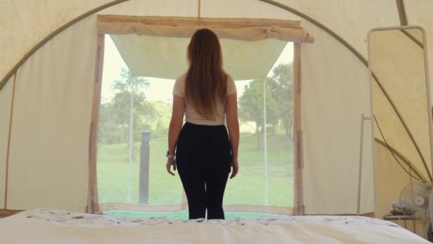 Visão traseira de turista feminino em férias na tenda moderna com cama. Desintoxicação digital — Vídeo de Stock