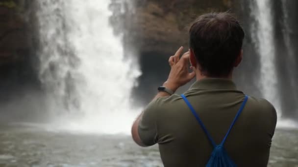 Reisefotograf Mann auf Felsen schießt Wasserfall für soziales Netzwerk — Stockvideo