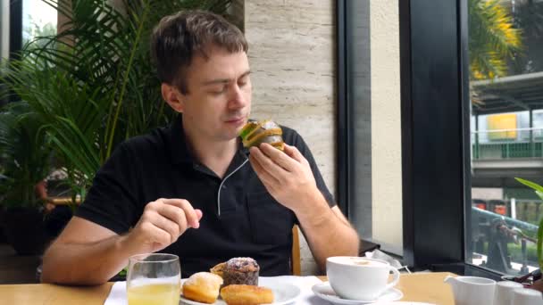 Pequeno-almoço doce fresco, homem feliz comer croissant francês no restaurante ou café — Vídeo de Stock