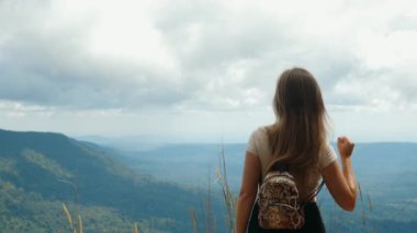 Sırt çantalı kadın turist elini kaldırıyor, kazanan jest yapıyor.
