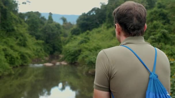 자연 경관 속에서 모험 여행을 하는 남자 관광객의 뒷모습 — 비디오
