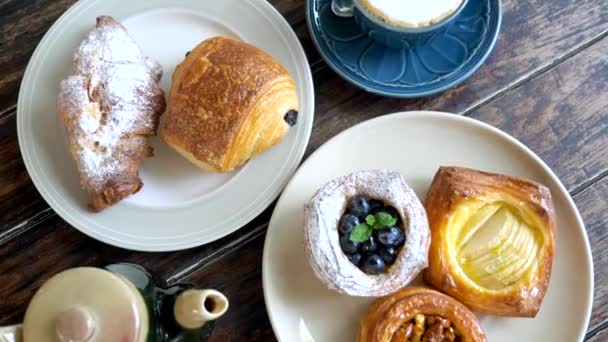 Bovenaanzicht van gebak op borden met theepot en kopje koffie, Morning sweet food — Stockvideo