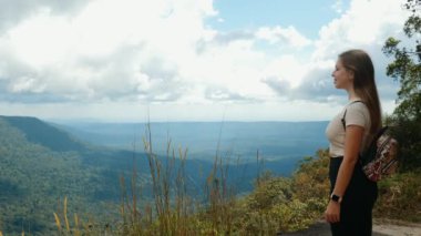Sırt çantalı gezgin kadın dağın tepesinde duruyor.