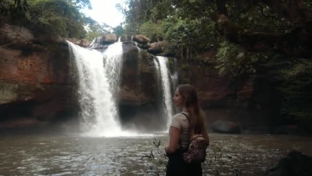 Giovane donna di viaggio sentendosi libero vicino alla cascata tropicale, godere della natura nella foresta — Video Stock