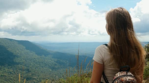 Sırt çantalı bir kadın dağın tepesinde duruyor, yazın tadını çıkarın. — Stok video
