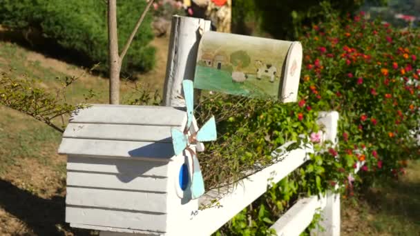 Two cute, rustic mailboxes on a white fence next to cute Provence style cottage — Stockvideo