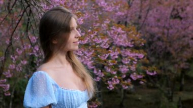 Bahçedeki gülümseyen kadının portresi çiçek açan pembe sakura ağacıyla
