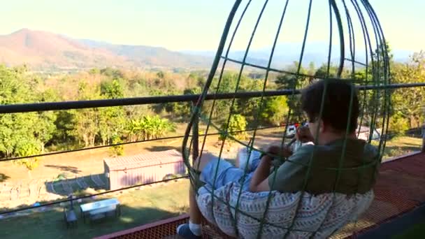 Hombre de viaje en la cafetería de la naturaleza con silla colgante, comer pastel y disfrutar de la puesta de sol — Vídeo de stock