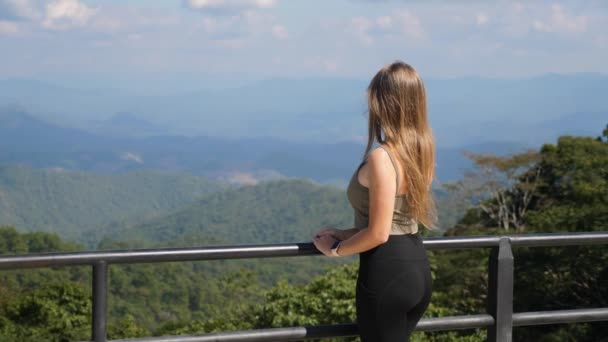 Vrouw genieten van uitzicht op de bergen vanuit het oogpunt. Achteraanzicht van vrouwelijke reiziger — Stockvideo