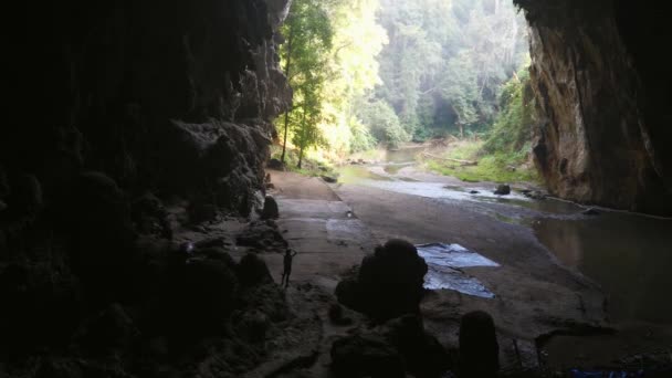 Жінка-дослідник у темній печері, дивлячись на відстань, спробуйте знайти вихід з печери — стокове відео