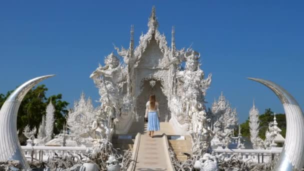 На задньому плані - жінка в сукні, що ходить у Білому храмі або Ват Ронг Кхун. — стокове відео