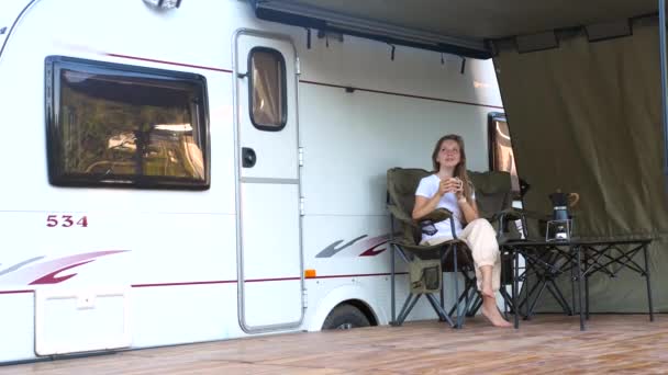 Mulher sentado perto de reboque motorhome moderno e beber café quente — Vídeo de Stock