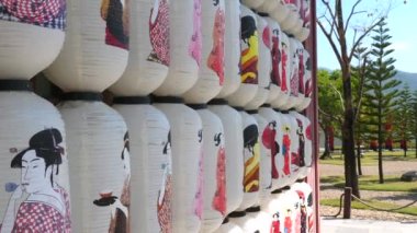 Geleneksel Japon kağıt fenerleri bahçede asılı ve arka planda dağlar var.