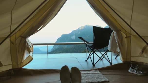 女性の足はリラックスしてキャンプテントから山の谷の景色を楽しむ — ストック動画