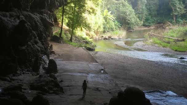 Femme méconnaissable explorateur silhouette dans la grotte sombre descend à la rivière — Video