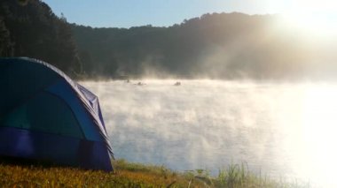 Sisin içinde nehrin yanında kamp çadırı. Göl kenarındaki orman sisli.