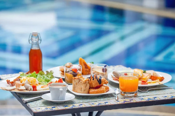 Tafel met heerlijk eten bij het mooie blauwe zwembad reizen in resort — Stockfoto