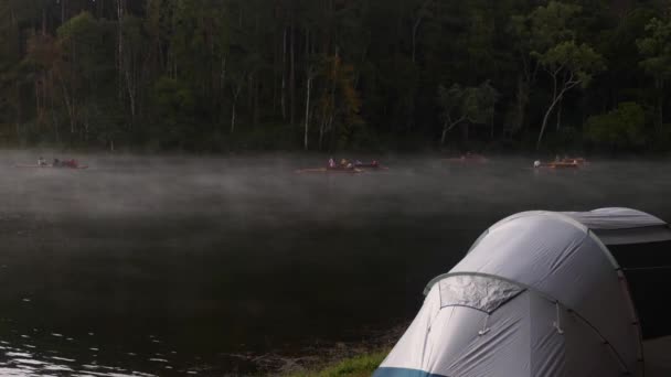 Кемпінг і намет біля озера з плотами під сосновим лісом рано вранці — стокове відео