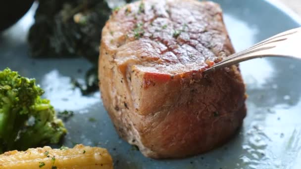 Detailní záběr čerstvého grilovaného steaku na talíři krájeného vidličkou a nožem na talíři — Stock video