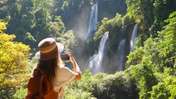 Vista posterior del blogger de viajes milenario en viaje o aventura en cascada — Vídeos de Stock