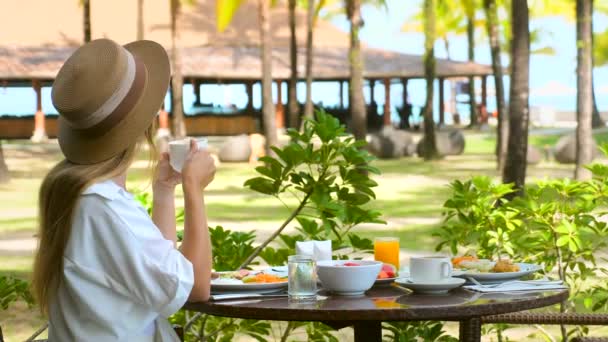 Όμορφη κοπέλα έχουν πρωινό σε υπαίθριο καφέ με καταπληκτική θέα τροπικό νησί — Αρχείο Βίντεο