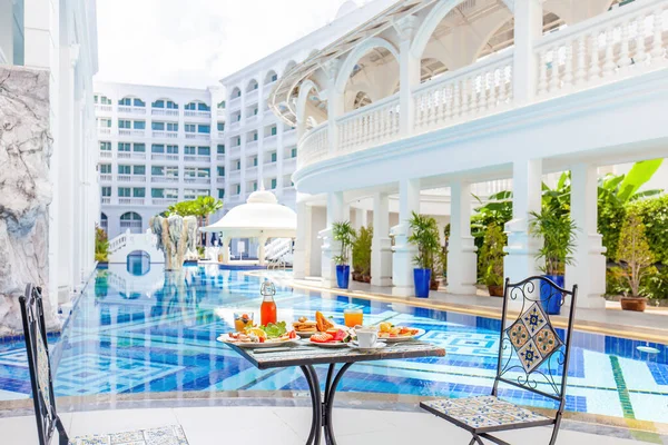 Tavolo con cibo delizioso presso la bella piscina blu viaggiare in resort — Foto Stock