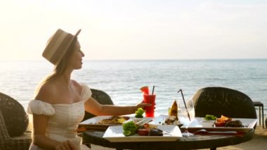 Romantik genç bayan tatilde. Restoranda yemek yer, kokteyl yudumlar.