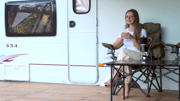 キャンパーRVバンのドアでコーヒーを飲む幸せな若い女性ホーム — ストック動画