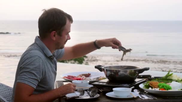 Muž vzít řeku krevety kleštěmi a dát ji do varu hrnce Shabu shabu hotpot stylu — Stock video