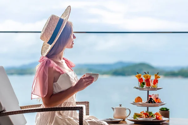 Beyaz elbiseli genç bayan çeşitli tatlılarla ikindi çayı içiyor. — Stok fotoğraf