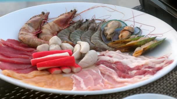 Тарелка с морепродуктами, ломтиками свинины и говядины для сукияки, барбекю или шабу шабу — стоковое видео