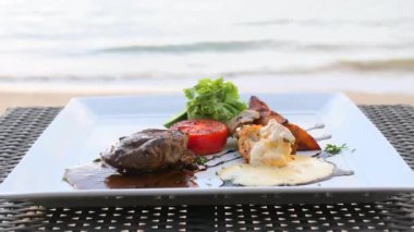 Plastik fileto mignon bifteği plaj masasında deniz dalgalı bir restoranda.