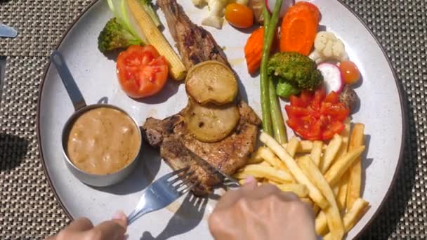 Mani di donna con forchetta e coltello tagliate carne arrosto fresca sul piatto con verdure — Video Stock