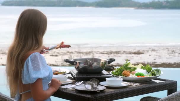 Женщина готовит и ест свежие морепродукты и мясо, традиционное японское блюдо — стоковое видео