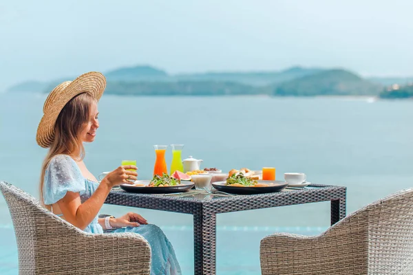 Yaz tatilinde hasır şapkalı bir kadın. Tropikal tatil köyü ve deniz manzaralı restoran — Stok fotoğraf