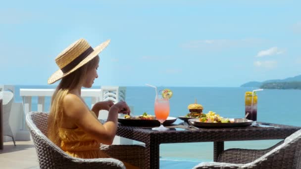 Γυναίκα με ψάθινο καπέλο στις καλοκαιρινές διακοπές. Τροπικό θέρετρο και εστιατόριο με θάλασσα — Αρχείο Βίντεο