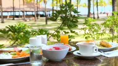 Güneşli yaz gününde kahvaltı. Lüks oteldeki güzel tropikal doğanın arasında.