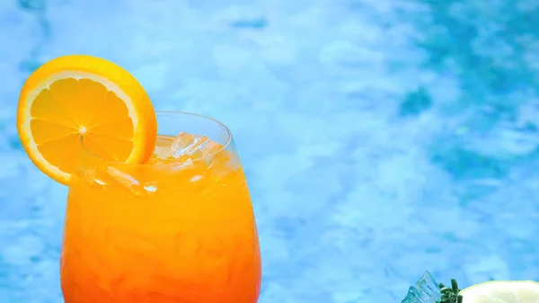 Cold non-alcoholic cocktail with ice and slice of orange and blue swimming pool