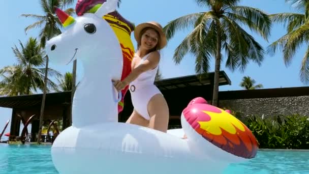 Счастливая женщина в купальниках веселится и танцует на надувном матрасе из единорога — стоковое видео