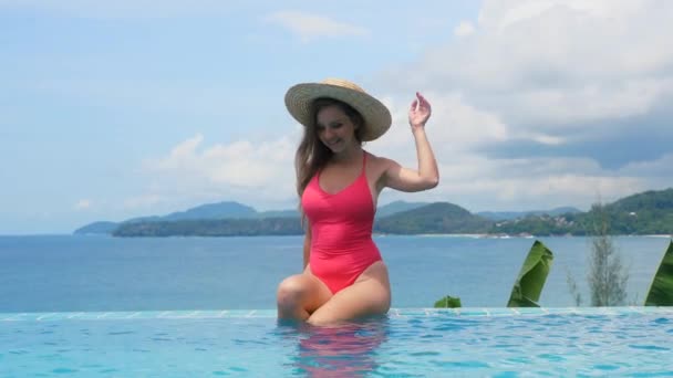 Jovem mulher viajando sentado na piscina azul, desfrutando de banhos de sol — Vídeo de Stock