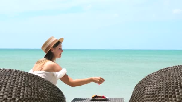 Mooi meisje met stro hoed genieten lunch op strand met turquoise zee oceaan — Stockvideo