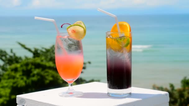 Dos vasos de cócteles tropicales fríos no alcohólicos sabrosos con océano — Vídeos de Stock