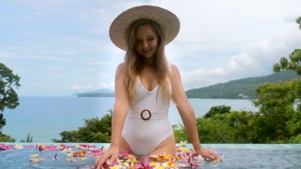 Woman relaxing in swimming pool with tropical flowers at luxury hotel spa resort — ストック動画