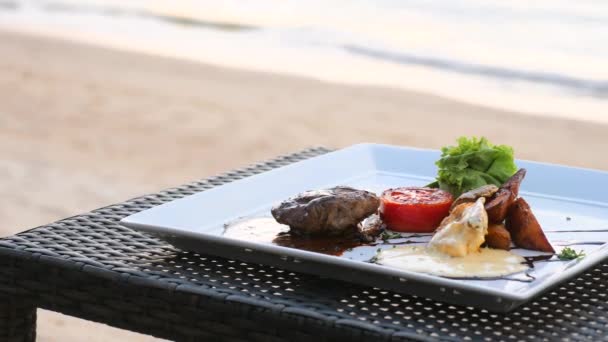 Grilled fillet mignon beef steak in resort restaurant on beach table by sea — ストック動画
