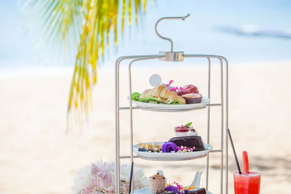 Middagthee op tropisch zandstrand met blauwe zee en palmblad op achtergrond — Stockfoto